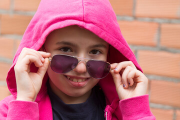 portrait of hipster girl with hoodie and sunglasses on the street