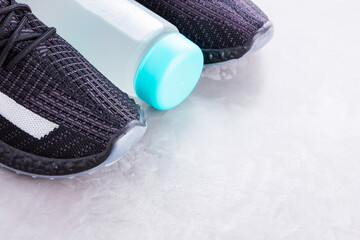 Fitness concept with sneakers and bottle of water. Sports equipment on a gray background. Healthy lifestyle concept. Copy space. Top view