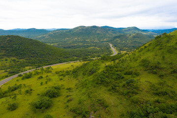 Obraz premium Panoramiczny widok z lotu ptaka na zielone łąki na zboczu góry w pogodny dzień, Panorama Route w RPA