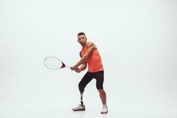 Fototapeta na wymiar Athlete with disabilities or amputee isolated on white studio background. Professional male tennis player with leg prosthesis training in studio. Disabled sport and healthy lifestyle concept.