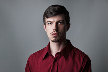 portrait of sirius purposeful handsome man. isolated over grey background. outer space. man with blue eyes, mustache, beard. person dressed in a red dress shirt. 30-34 years old. look to camera.