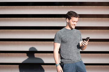 Handsome man looking at his cell phone before he starts running.