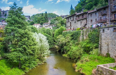 Fototapeta na wymiar Spain, Catalonia. Rupit - a small ancient town of stone in the territory of the Natural Park of the volcanic Garrotxa. Public pool./Rupit (The city of Witch) - a small ancient town of stone.