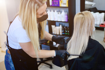 Hairdressing salon opened. Hairdresser with security measures for Covid-19, a woman in a medical mask, social distance, cutting hair with a medical mask and rubber gloves