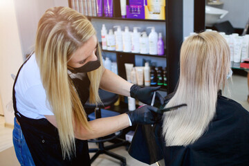 Hairdressing salon opened. Hairdresser with security measures for Covid-19, a woman in a medical mask, social distance, cutting hair with a medical mask and rubber gloves