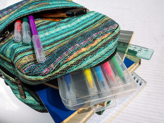 School bag with textbooks, notebooks and other educational accessories. Felt pens are in the pocket...