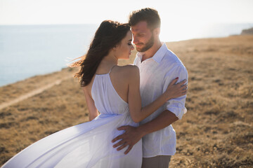 Beautiful young couple hugging in nature. People in white clothes.