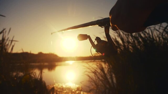 fisherman fishing fish silhouette on sunset. man recreation with fishing lifestyle rod outdoor catching fish at sunrise. hobbies fishing sport concept sunset. man relaxes with fishing rod