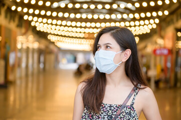 A young Asian woman is wearing protective mask shopping in shopping center, Coronavirus...
