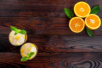 Refreshing orange juice with ice on dark wooden background top view flat lay copy space