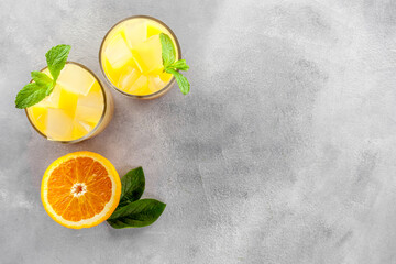 Chilled Orange Juice with Ice on gray stone background top view flat lay copy space