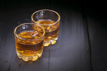 two glasses of cognac on a black tree