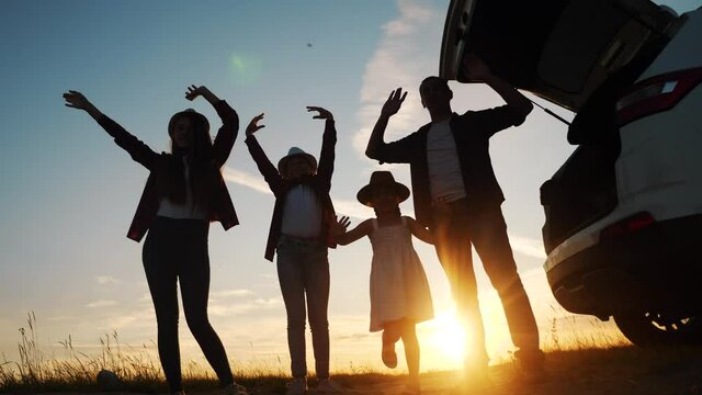 happy family wave goodbye campsite on a car outdoors silhouette at sunset. parents and kid children waving hands at the sunset nature. day off holiday friendly family dream teamwork concept. happy
