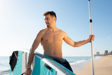 Attractive and athlete man  with a paddle surfboard on the beach