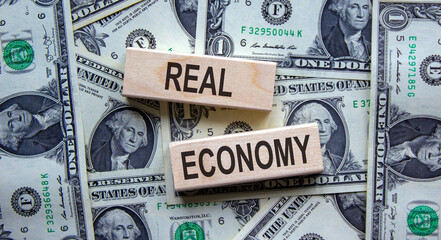 Concept words 'real economy' on wooden blocks on a beautiful background from dollar bills. Business...