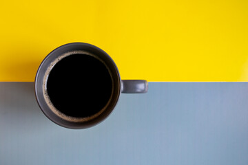A cup of black coffee in the morning on a yellow-gray background. cup of coffee on the background of a yellow table. Good morning, energy, motivation concept. Space for text