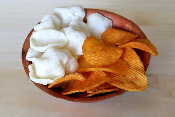 potato chips into bowl  on a wooden table close up