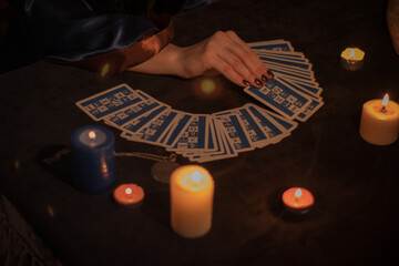 Fortuneteller hands close up. Mystical prediction of cards by candlelight.