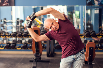 Fototapeta na wymiar A portrait of senior man doing workout before training in the gym. People, healthcare and lifestyle concept