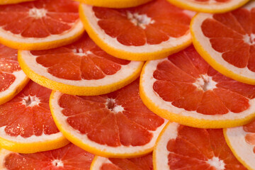 Bright red background with juicy slices of grapefruit. Healthy food background.