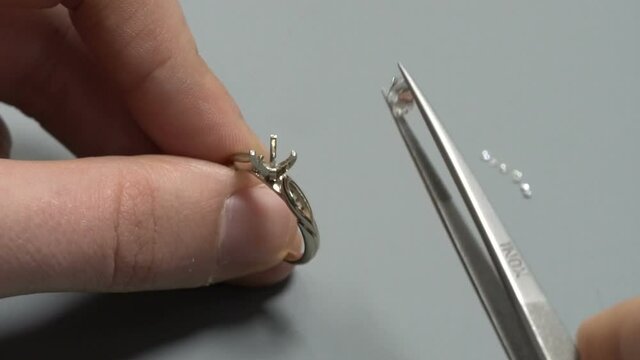 putting the diamond on the white gold solitaire ring. hand made diamond ring craftsman. jewelery product macro close up