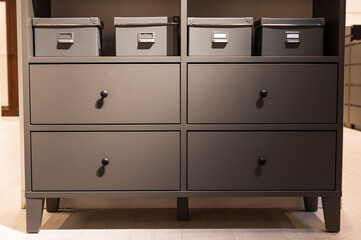 Closeup of a gray chest of drawers. A variant of simple furniture without decor and design in the interior.