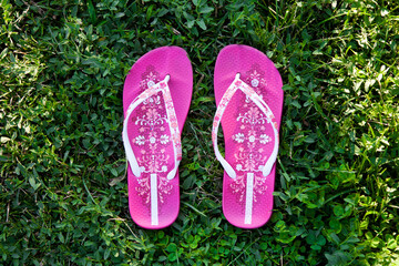 Top view closeup shot of a pair of casual pink slippers on the green grass