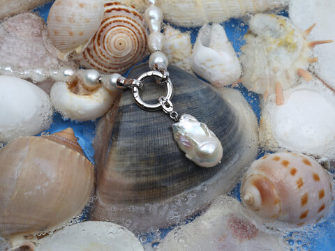 Baroque pearl necklace with pendant on marine shell background