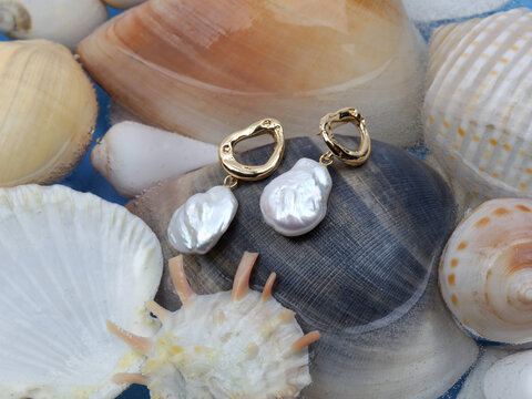 Pair of baroque pearl gold earrings on marine shell background