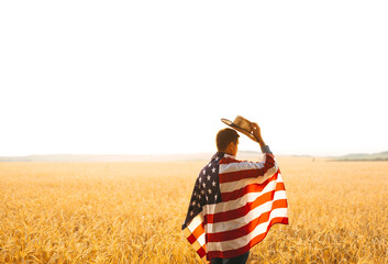 Young caucasian farmer energetically raised the US flag in a picturesque field of wheat.	
