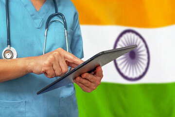 Surgeon or doctor using a digital tablet on the background of the India flag. Medical equipment or medical network, technology and diagnostics in India.