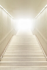 Up stairs going toward strong light. Stairs going up. White modern staircase.