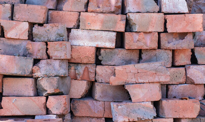 A stack of red clay bricks. Rows of old dirty cracked bricks. Architectural texture. Clay bricks.