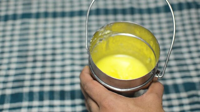 A Person showing Pure Cow ghee from stainless steel container