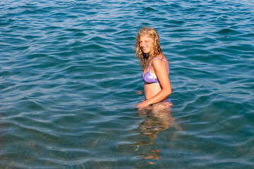 Obraz premium young girl in a swimsuit swimming in the sea. Looks at us