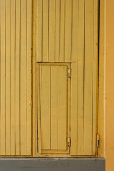 Fototapeta premium The wall and large double wooden doors are painted yellow