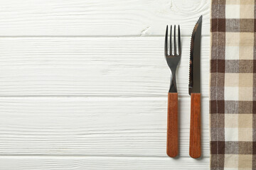 Tablecloth and cutlery on white wooden background, space for text