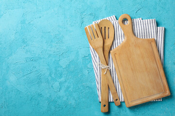 Napkin, cutlery and cutting board on blue background, space for text