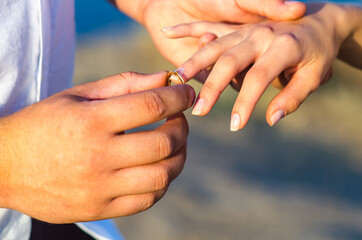  Young man puts a wedding ring on the finger of his bride