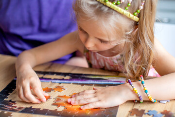 Father and daughter assemble the puzzle while sitting at the table. Games during rain and bad weather, quarantine. Family relaxing educational games at home.