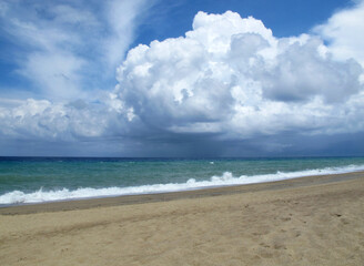 Fototapeta na wymiar Sandy beach on a warm summer day, turquoise sea with glebe waves and large rain clouds over the sea, Italy, Calabria