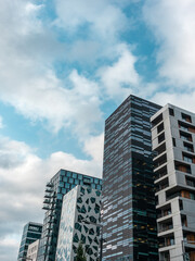 Fototapeta premium Modern business district in Oslo on cloudy epic sky, Norway, Scandinavia. Office urban buildings of the Barcode project in Bjorvika district low angle