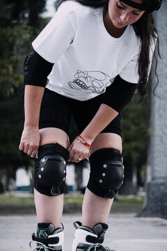 Joven mujer ajusta sus rodilleras antes de patinar