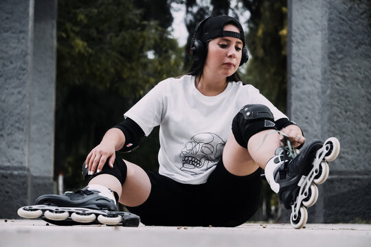 Joven mujer skater ata las agujetas de sus patines en el suelo