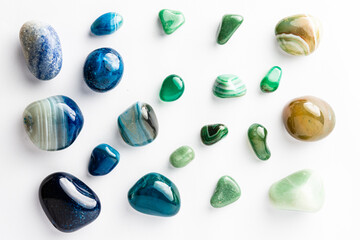 Blue and green semi-precious stones arranged neatly on a white background