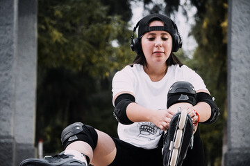 Joven mujer skater ata las agujetas de sus patines en el suelo