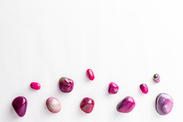 Pink semi-precious stones arranged neatly with a empty space above them on a white background