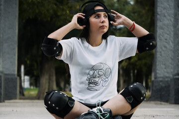 Joven mujer skater está en el suelo acomodando sus audífonos