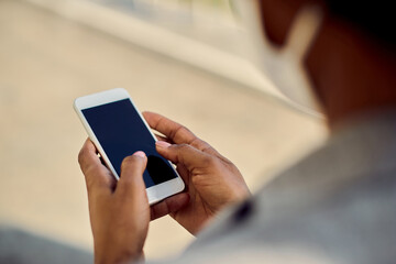 Close-up of African American businesswoman texting on cell phone outdoors.