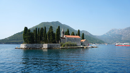 A small island lies in the middle of the water, on the island a small church on a background of...